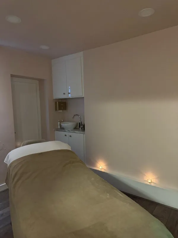 A treatment room lit by candles with a warm blanket on the couch
